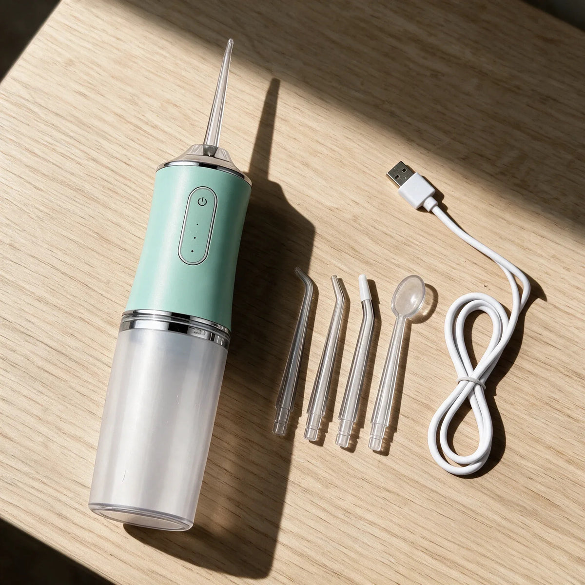 PureStream flosser with four nozzles and USB cable on a wooden table